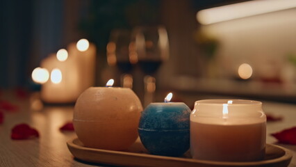 Closeup burning candles standing on dark kitchen. Two wine glasses waiting date.