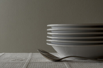 Spoons and soup plates stacked on a white tablecloth
