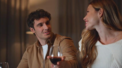 Romantic people enjoy wine spending evening together in dark apartment close up.
