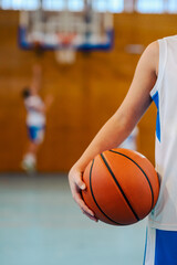 Close up of junior athlete's hand holding a basketball at indoor court