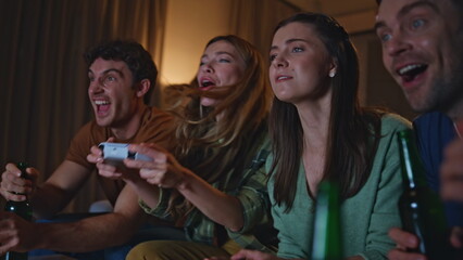 Emotional girls playing video game on home couch with happy friends close up. 
