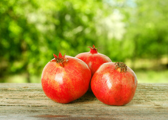 Delicious ripe pomegranates on wooden table against blurred background