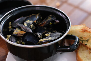 Process of cooking mussels and oysters, ingredients for traditional pasta with seafood. Cooking pails in kitchen. Frying pan and boiled mussels. Modern kitchen and cooking utensils. Mussels in sauce