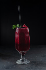 berry smoothie in a glass on a black background from a shaker