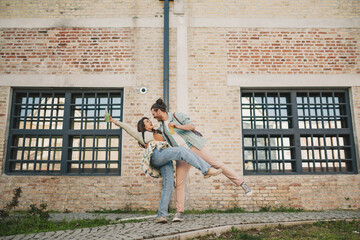 Young playful couple hugging and having drinks at old town. Copy space