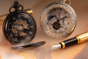 Beautiful pocket watch and vintage fountain pen on rustic wood, selective focus.