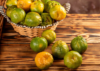 Orange ponkan on rustic wood, black background, selective focus.