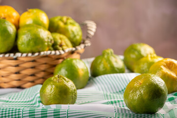 Orange ponkan on rustic wood with green tablecloth, dark background, selective focus.