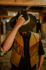 Front view of a cowboy greeting while standing at horse stall.