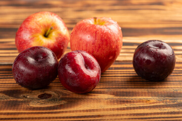 Apples and plums on rustic wood, selective focus.