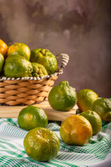 Orange ponkan on rustic wood with green tablecloth, dark background, selective focus.