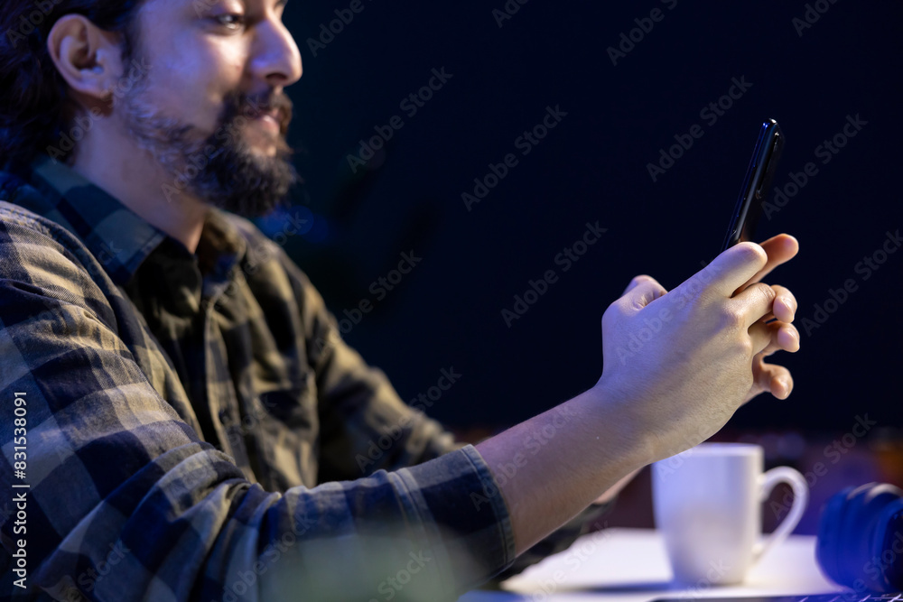 Aufkleber cheerful male student is utilizing his mobile device to check social media while seated at his desk.
