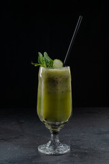 green smoothie in a glass on a black background