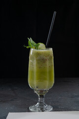 green smoothie in a glass on a black background