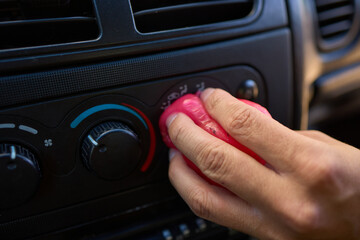 Fototapeta premium A person is seen holding a pink object near the air vent of a car