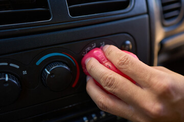 A person is seen holding a pink object near the air vent of a car