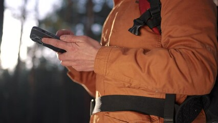 travel navigation. man tourist looking for a way in a smartphone navigation in winter in a forest park. male hacker navigates in the forest navigation looking close-up for a way in winter in park