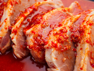 Pork chops in red Asian style marinade with chilly pepper, close up shot. Fine pork meat for grill...