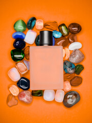 A bottle of cologne is placed on top of a pile of colorful stones. The bottle is empty, and the stones are of various shapes and sizes. Concept of relaxation and leisure, as the cologne bottle