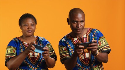 African american couple playing mobile videogames on camera, having fun with online tournament over...