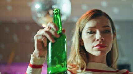 Drunk girl dancing alone in empty dark apartment close up. Woman holding beer