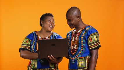 Husband and wife searching information on online website, holding laptop in front of camera for...