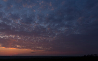 Landscape with bloody sunset. Panorama. Tragic gloomy sky. The last flashes of the sun on the storm...