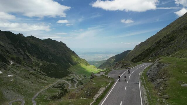 Aerial drone shot of three cyclists ride together a gravel bicycles on Transfagarasan road in the mountains, Transylvania, Romania. Fun bikepacking adventure on a weekend. Healthy outdoor lifestyle.