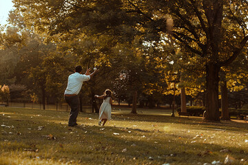 Fototapeta premium A father and daughter playing catch in the park, enjoying the outdoors and spending quality time together.