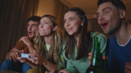 Competitive players enjoy video game at apartment sofa late evening close up.