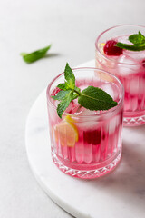 Raspberry cocktail with ice in a glass on a light background