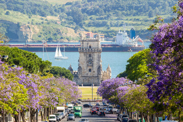 Belem Tower, Jacaranda Blooming Purple Blue Trees, Large Barge and Sailing Boat on Sunny Day....