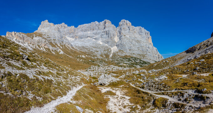 Panorama of the Dolomites mountains on a sunny day, blue sky with soe clouds. Beautiful mountians of Alpi Dolomiti in Italy, South Tirol alpine range in autumn