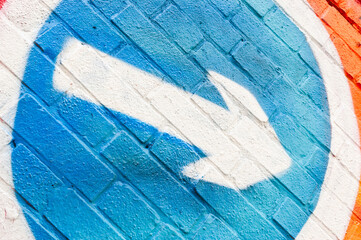 White arrow graffiti sprayed on blue brick wall