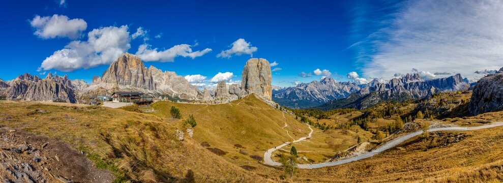 Panorama of the Dolomites mountains on a sunny day, blue sky with soe clouds. Beautiful mountians of Alpi Dolomiti in Italy, South Tirol alpine range in autumn