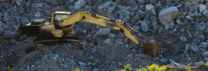 Excavator digging earth in canyon, construction concept