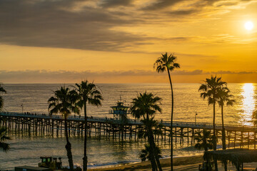 Obraz premium A beautiful golden beach sunset on a summer evening with people enjoying the scenery