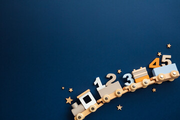 Educational wooden toy train with colorful number shaped blocks on a dark blue background. Concept of playful learning for children.