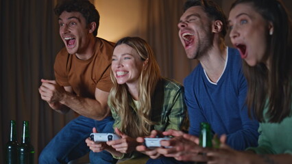 Excited friends rejoicing videogame at evening meeting close up. People playing