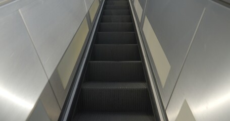 Looking straight ahead while riding an escalator upwards, outdoors in daylight