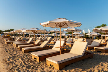 Beautiful tropical sunset. Sun on the beach casts a warm and soothing glow over the tranquil waters, while umbrellas provide shade. Relaxing sunrise leisure resort