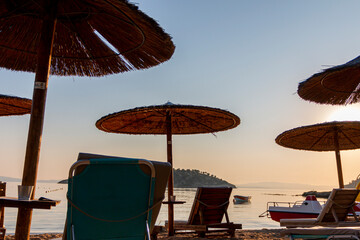 Beautiful tropical sunset. Sun on the beach casts a warm and soothing glow over the tranquil waters, while umbrellas provide shade. Relaxing sunrise leisure resort