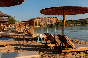 Beautiful tropical sunset. Sun on the beach casts a warm and soothing glow over the tranquil waters, while umbrellas provide shade. Relaxing sunrise leisure resort