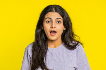 Fototapeta premium Oh my God, Wow. Excited amazed winner woman raising hands in surprise looking at camera with big eyes, shocked by sudden victory celebrating success achievement good news. Girl on yellow background