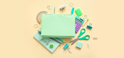 Composition with blank notebook and different school stationery on beige background