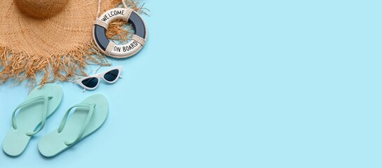 Sunglasses, ring buoy, flip-flops and beach hat on light blue background with space for text