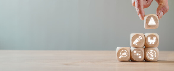 Incident management concept, Hand holding wooden block on desk with incident, alert, investigation, analysis, identify and restore icon on virtual screen.