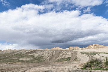 Landscape of a recreational dirt bike trail area for motocross riding in the secluded hilly country with blue sky and white and dark storm clouds