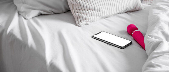 Vibrator and mobile phone on bed in morning, closeup