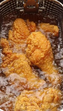Deep fry chicken drumstick in deep fryer. frying in hot boiling oil. Close up shot